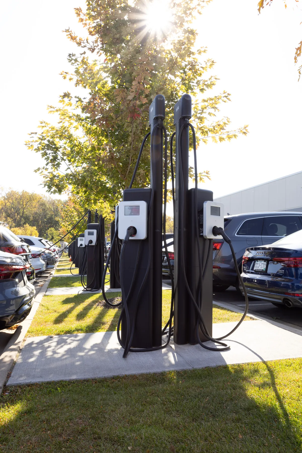 Audi electric vehicle charging stations lined up beside parked cars.