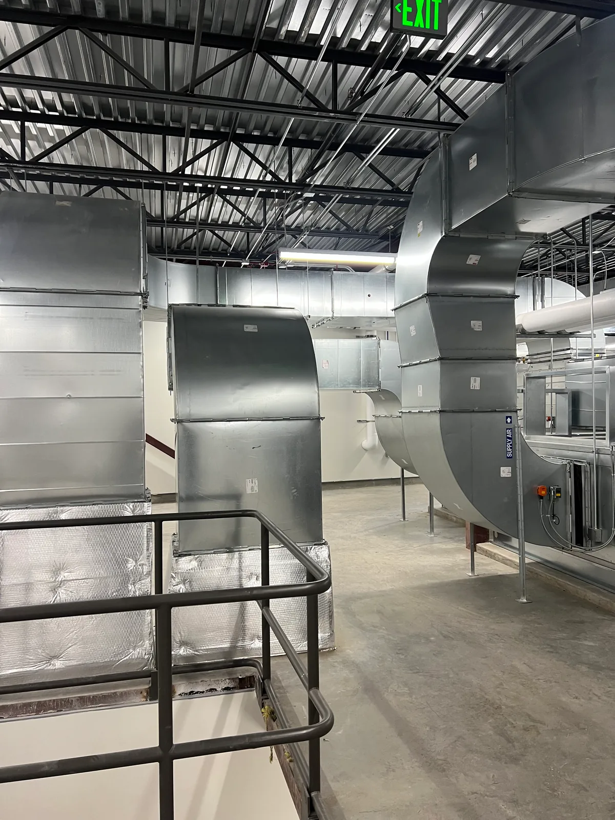Finished sheet metal ductwork and railings inside a commercial facility.