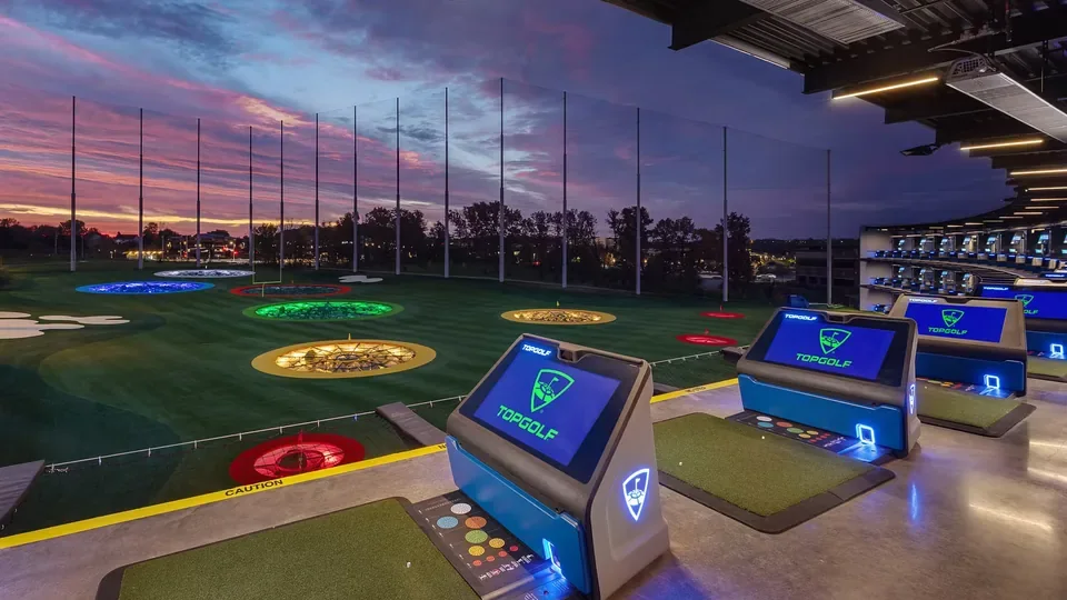 Illuminated Topgolf driving bays and targets at dusk.