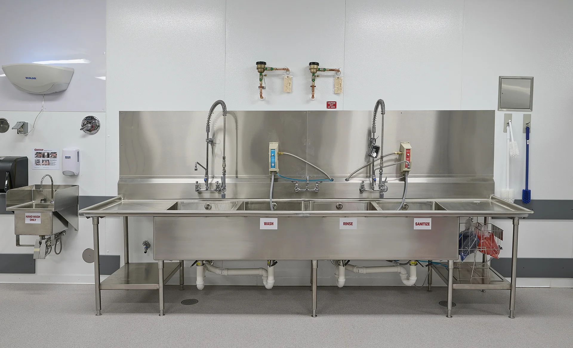 Stainless-steel sinks and faucets in a finished Costco plumbing installation.