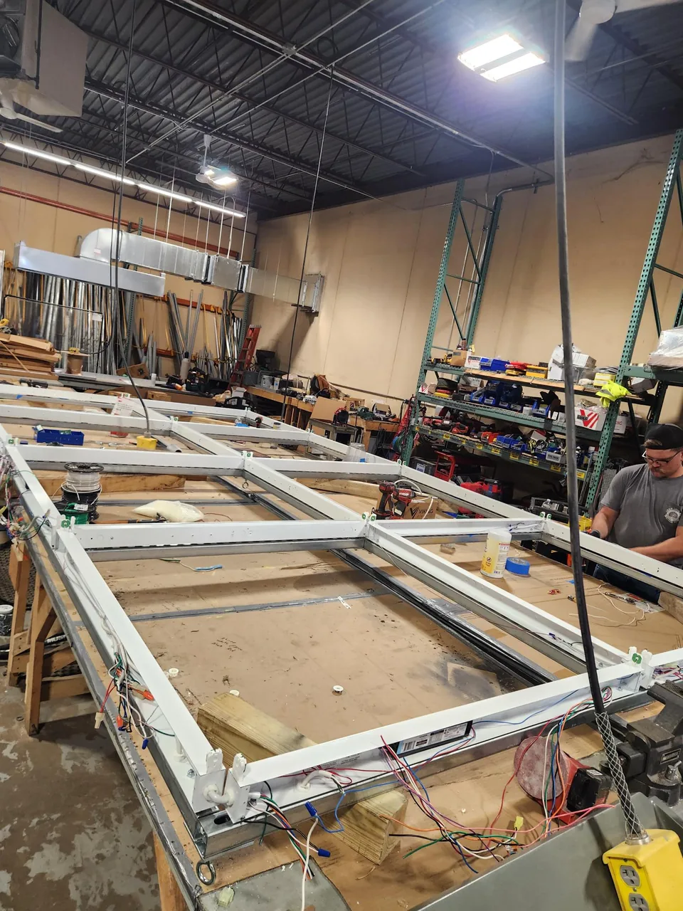 A crew member assembling custom lighting frames and wiring on a workbench in the pre-fabrication shop.