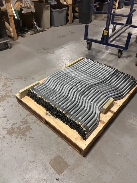 Matching bent metal pipes with fittings organized on a pallet in the shop.
