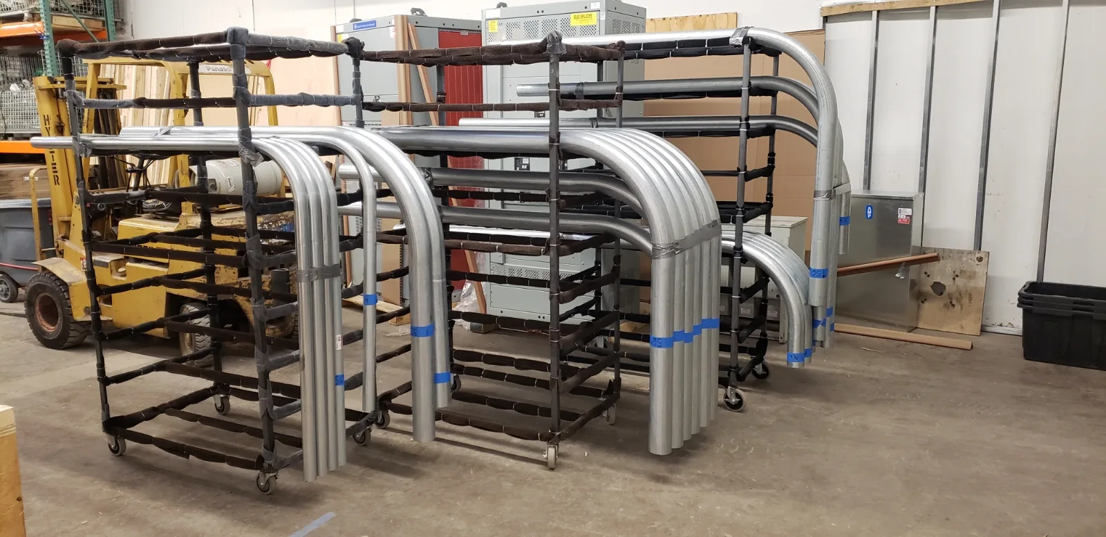 Rows of bent metal pipe organized on racks in Muska's pre-fabrication shop.
